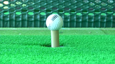 Golfer hits golf ball off of automatic tee swing training Stock Footage 125344389