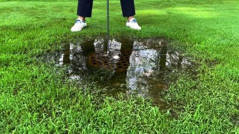 Golfer Hitting the Golf Ball with Her Golf Club in a Water Pond Stockbeeldmateriaal 284019072