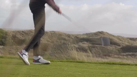 Golfer hitting powerful drive, shot through long grass Stock Footage 104563405