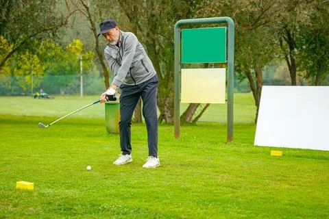 Golfer performs a strong golf shot to fairway Stock Photos
