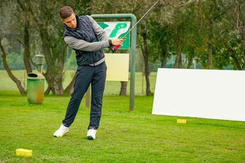 Golfer performs a strong golf shot to fairway Stock Photos