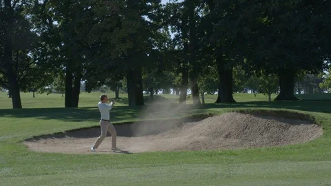 A golfer plays a shot out of a sand trap in slow motion. Video stock 80417702