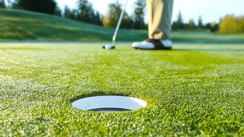 Golfer on putting green misses the cup just barely Stock Footage