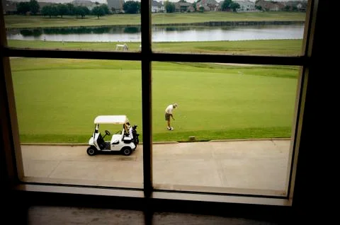 Golfer on putting greenman and a golf cart Stock Photos