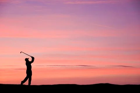 Golfer silhouette against stunning sunset sky Stock Photos
