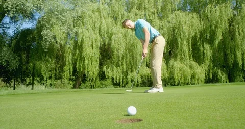 A golfer sinks a putt. Vídeos de archivo 112015070
