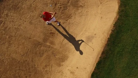 A Golfer successfully chips a shot out of a sand trap. Video stock 86557684
