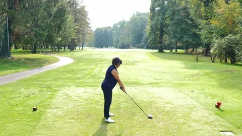 Golfer Teeing Off and Hitting with Her Driver the Golf Ball on Golf Course Stockbeeldmateriaal 219011489