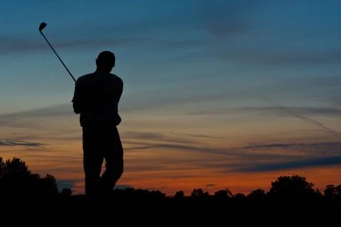 Golfer teeing off at dusk Foto stock