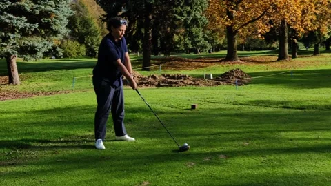 Golfer Teeing Off with Her Driver on Golf Course in a Sunny Day in Autumn Stockbeeldmateriaal 220477417