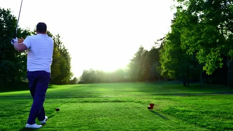Golfer Teeing Off with His Driver on Golf Course with Sunlight and Lens Flare Stockbeeldmateriaal 220477595