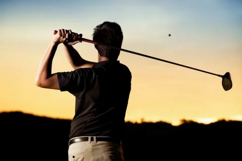 Golfer teeing off at sunset. Foto stock
