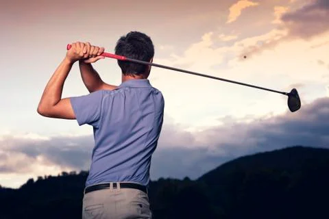 Golfer teeing off at sunset. Stock Photos