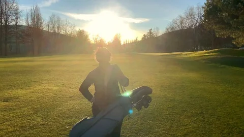 Golfer Walking on the Golf Course with Her Golf Bag and Sunlight Stockbeeldmateriaal 126690951