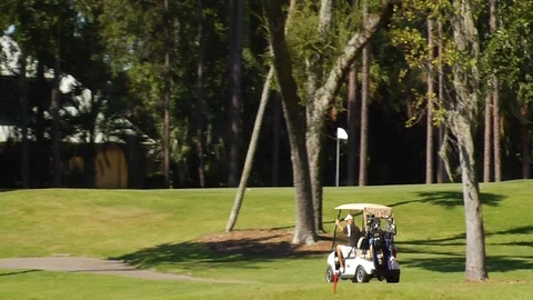 Golfers on cart path moving to next hole past green Stock Footage 117249373
