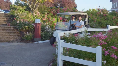 Golfers drive cart down walkway Stock Footage 60098705