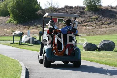 Golfers in golf cart driving down a path Stock Photos