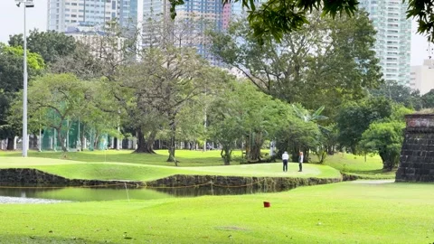 Golfers Playing on a Lush Green Course Near Manila City Skyline Vídeos de archivo 331551173