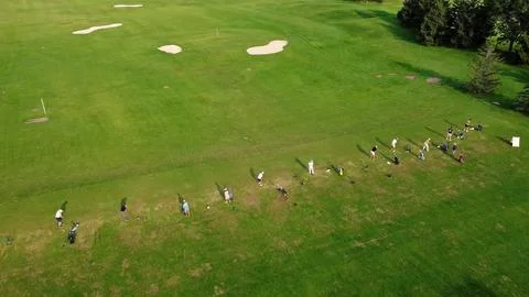 Golfers Practicing at Driving Range on Green Field. Aerial view of a group of Stock Photos