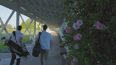 Golfers walk down driving range Stock Footage 60111051