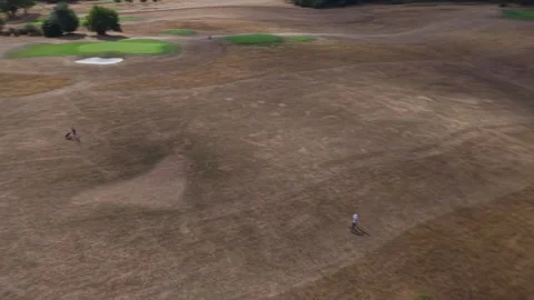 Golfers walking on dry golf course fairway near green putting green, aerial view Vidéo 343783336
