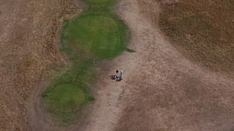 Golfers walking on golf course carrying trolley bags, top down aerial view Stock Footage 343783341