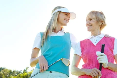 Golfing buddies with mom. Two attractive woman holding golf clubs and standing Stock Photos