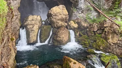 Golling Waterfall flows through a natural rock arch and boulder-filled gorge Stock Footage 341712413