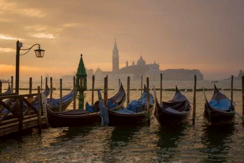 Gondolas by Saint Mark square during sunrise with San Giorgio di Maggiore chu Stock Photos