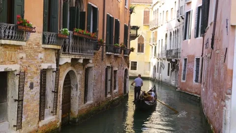 Gondolier Rowing Passengers Through Venice Canal from Rear View Stock Footage 339221562