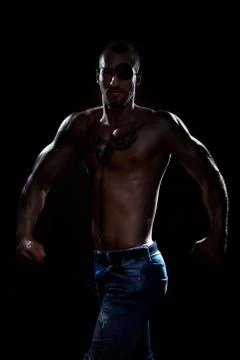 Good developed man with eye patch and tattoo posing in studio Stock Photos