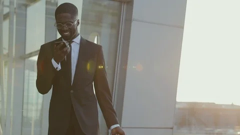 Good-looking Afro-American in a stylish Suit uses his Smartphone for talking Video stock 88559959