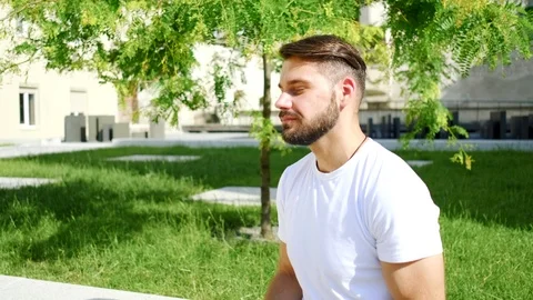 Good-looking bearded young guy wearing white headphones and listening inflammato Stock Footage 112356521