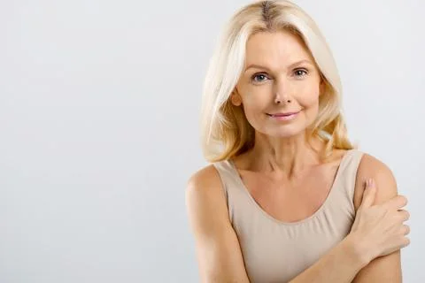 Good-looking beautiful middle-aged woman posing in studio over grey Foto stock