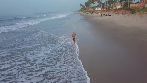 A Good looking black fit man running along the coastline of a paradisiac Vídeo Stock 125397665