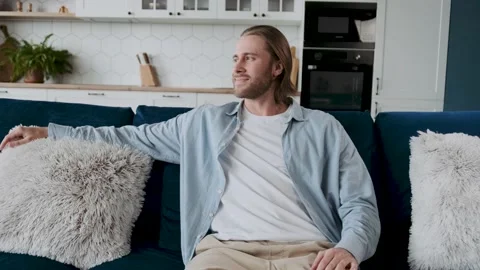 Good looking blond bearded man looking aside, chiiling on a sofa wearing casual Stock Footage 196246396