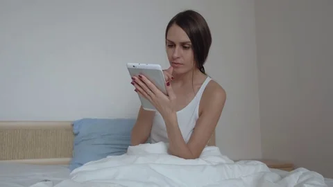 Good looking brunette with a tablet in her bedroom Stock Footage 82729135