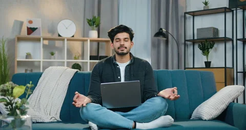 Good-looking calm young bearded guy with closed eyes sitting in relaxed pose on Stock Footage 150118379
