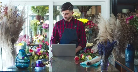 Good-looking Caucasian man working, using laptop in modern flower store Stock Footage 138748482