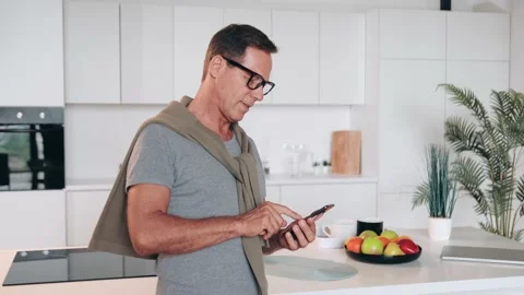 Good looking caucasian Middle Aged Man Using Smartphone In Bright Home Interior Stock Footage 231703920