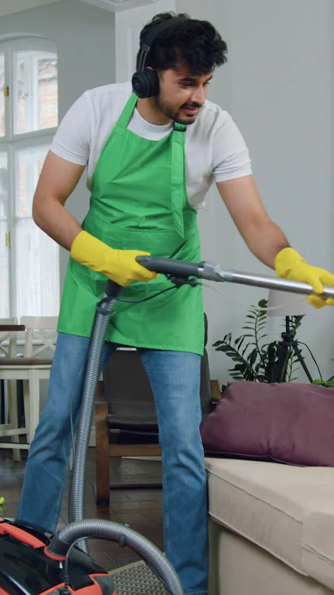 Good-looking confident smiling young bearded cleaner in green apron and yellow g Stock Footage 327869364