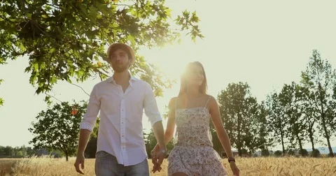 Good looking couple walking and kissing across a wheat field Stock Footage 77117583