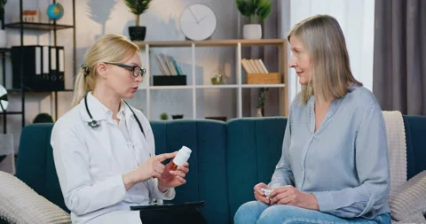 Good-looking experienced friendly female doctor giving bottle of pills to her Stock Footage 151539526