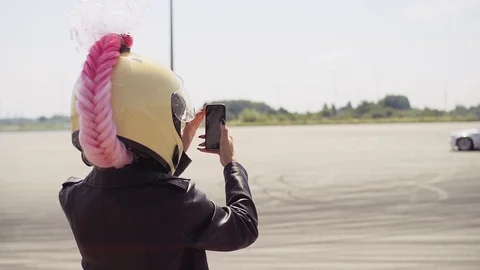 Good-looking girl with pink braid holding smartphone in hand and making video of Stock Footage 95960369