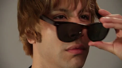 Good looking guy removes and wears a cooling glass in front of camera Stock Footage 22843393