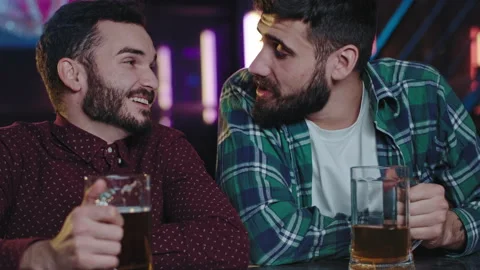 Good looking guys in front of the camera while sitting on a pub drinking beer Stock Footage 134182338