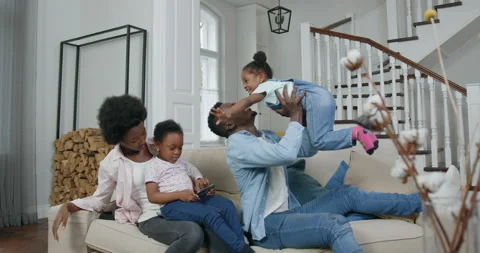 Good-looking happy loving black man lifting daughter on his hands,sitting on Stock Footage 144343486