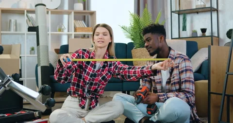 Good-looking happy young mixed race couple sitting on the floor in their new Stock Footage 158560641