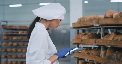 Good looking lady with a new big tablet take some photos of a fresh baked bread Stock Footage 122935097