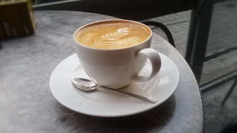 Good looking latte coffee and a spoon on the table at cafe. Smooth pan motion. Stock Footage 121887714